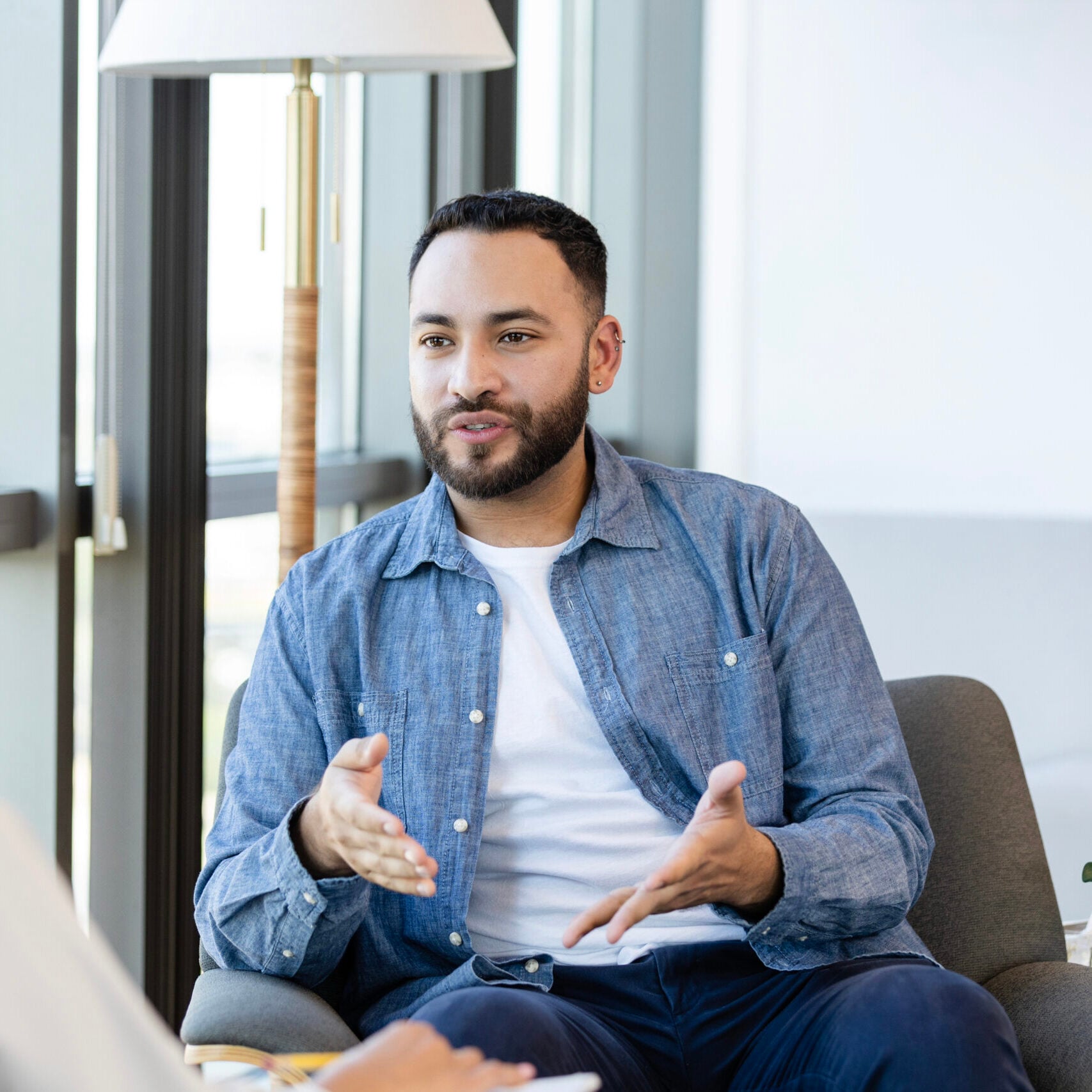 A young man gestures as he shares something during a therapy session.